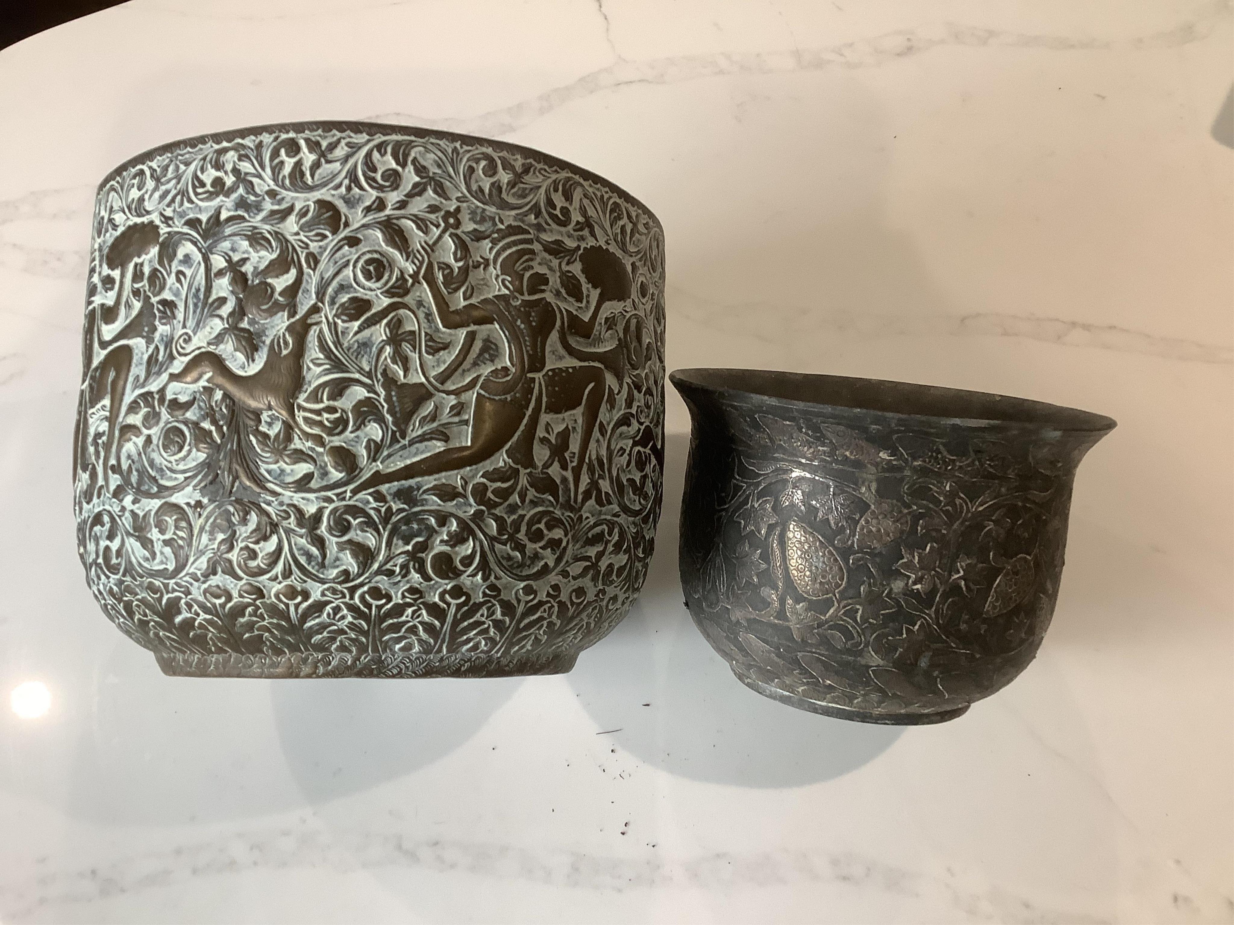 An Indian bidriware jardiniere decorated with fruiting plants and fish, 12.5cm and an embossed brass jardiniere decorated with monkey gods, 17.5cm.
